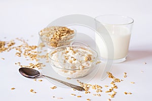 Oatmeal in a plate with a glass of milk and a spoon on a white background