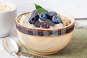 Oatmeal porridge with berries still life, blueberries, raisins, birch, cut down
