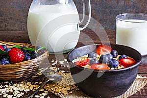 Oatmeal porridge with blueberries and strawberries with jug of milk