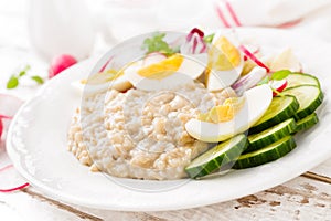 Oatmeal porridge with boiled egg and vegetable salad with fresh radish, cucumber and lettuce. Healthy dietary breakfast