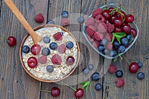 Oatmeal porridge in bowl topped with fresh blueberries, raspberries and cherries