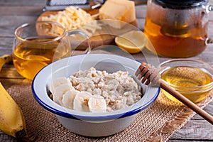 Oatmeal porridge with cheese and banana on a white plate on a wooden background