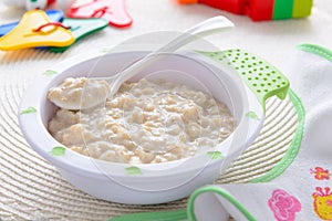 Oatmeal porridge for children nutrition on white tablecloth with bib