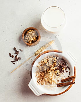 Oatmeal porridge with nuts, cinnamon and chocolate, a glass of milk. Breakfast, healthy food. Copy space. Good morning