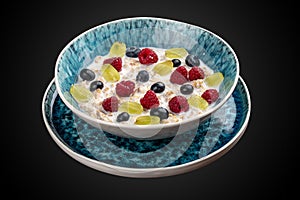 Oatmeal porridge with seasonal berries. On a dark background. Breakfast