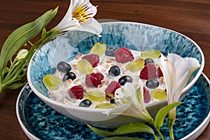 Oatmeal porridge with seasonal berries. On a wooden background. Breakfast