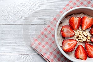 Oatmeal Porridge with Strawberries, Almonds in white bowl. Healthy Breakfast with Oatmeal and Fresh Organic Strawberry. vegan food