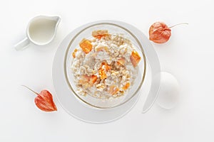 Oatmeal with pumpkin and nuts, egg and a jug of milk on a white background.