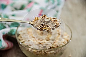 Oatmeal on a spoon against the background of a glass of milk and a plate of porridge.