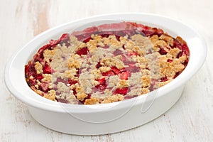 Oatmeal strawberry crumble in white dish on white background