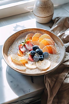 Oatmeal topped with fresh fruits in a bowl on a marble surface.
