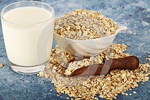 Oatmeal in a white bowl with a glass of milk on a white blue background. A healthy, nutritious morning breakfast. Oat milk. Health