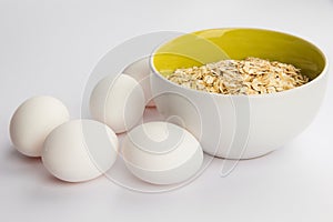 Oatmeal and white chicken eggs on a white background