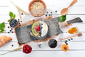 Oatmeal with yogurt and fruits and berries. Kiwi, blueberry, raspberry. On a wooden background. Top view.