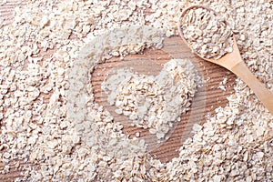 Oats and heart in a woodwn background with wooden spoon