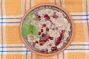 Oats porridge with fresh red currants in bowl, top view