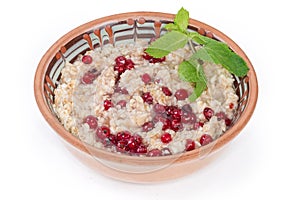 Oats porridge with red currants in bowl on white background