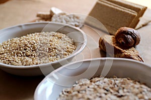 Oats and rice in a bowl. Rice cakes and bread in background. Foods high in carbohydrate.