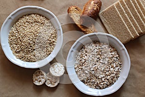 Oats and rice in a bowl. Rice cakes and bread in background. Foods high in carbohydrate.