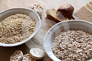 Oats and rice in a bowl. Rice cakes and bread in background. Foods high in carbohydrate.