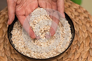 Oats Trickling from Hand into Bowl. Hand sprinkling rolled oats into a black bowl