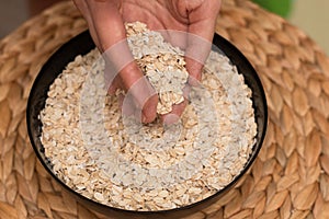 Oats Trickling from Hand into Bowl. Hand sprinkling rolled oats into a black bowl