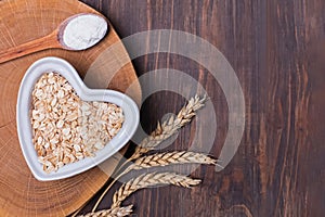 Oats, wheat ears and flour in the spoon on the wooden table