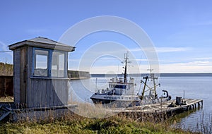 Ob River bank with a wooden booth, a pier and a fishing boat in summer