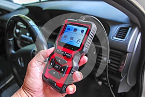 OBD2 scanner in hand, car diagnostic tool and code reader to check engine light, read and clear DTCs