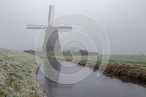 The Obdammer mill in Berkmeer, North Holland, is shrouded in mist on this December autumn day. There is a thin layer of ice on the