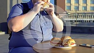 Obese bachelor eating fast food hamburger, unhealthy lifestyle, overweight