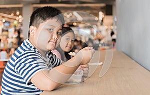 Obese brother and sister eating box lunch in food court