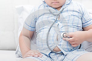 Obese fat boy check stomach by stethoscope