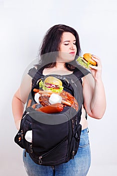 Obese fat young woman with a great backpack full of junk food on