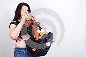 Obese fat young woman with a great backpack full of junk food on