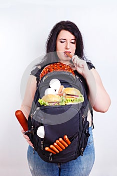 Obese fat young woman with a great backpack full of junk food on