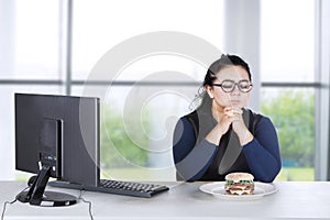 Obese female hesitates eat burger at home
