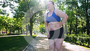 Obese girl jogging, suffocating, feels belly pain after tiresome workouts