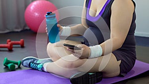 Obese lady scrolling sport app on her smartphone, watching weight loss results photo