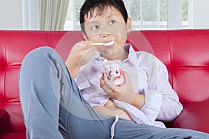 Obese little boy eating tasty ice cream at home