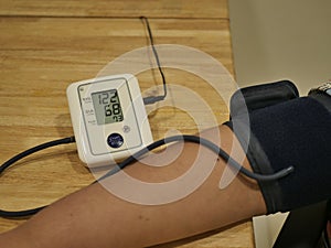 An obese male boy measures his blood pressure by himself.