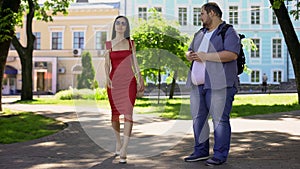 Obese male sadly looking at pretty slim lady in dress, appearance insecurities