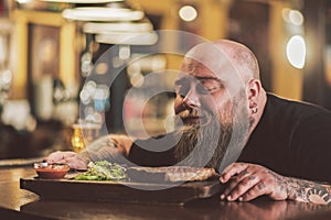 Obese male savoring grilled meat in pub