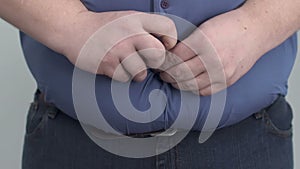 Obese man buttoning shirt on enormous tummy, fight with insecurities, obesity