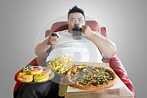 Obese man drinking and overeating on the sofa photo