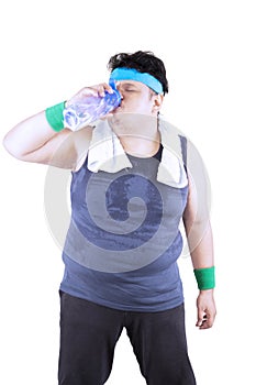 Obese man is drinking after workout on studio