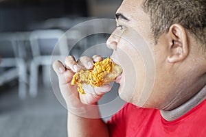 Obese man eating tasty crunchy fried chicken