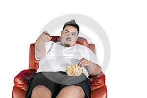 Obese man eats popcorn during watch television