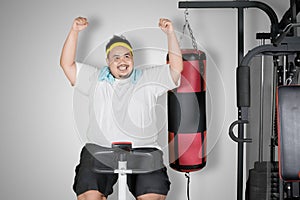 Obese man expresses happy on an exercise bike