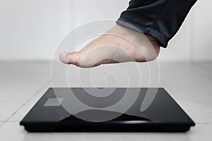 Obese man feet step on the weighing scale